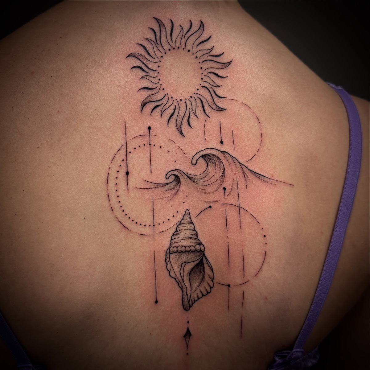 Ein Fineline-Tattoo auf dem Rücken einer Frau