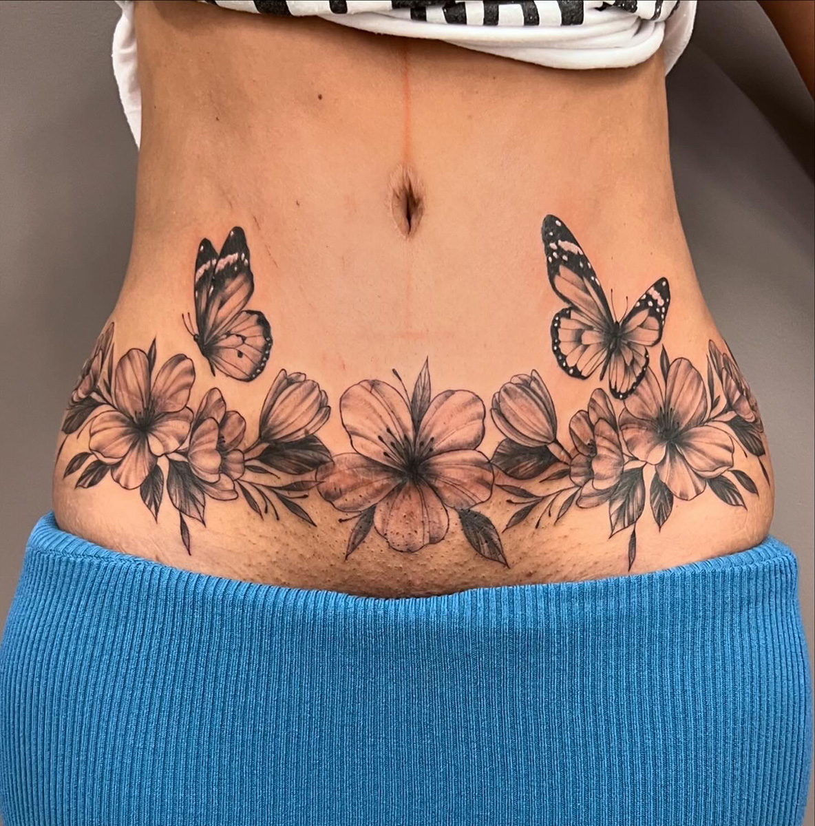 Wunderschöner Blumenring mit Schmetterlingen - Tattoo auf Bauch